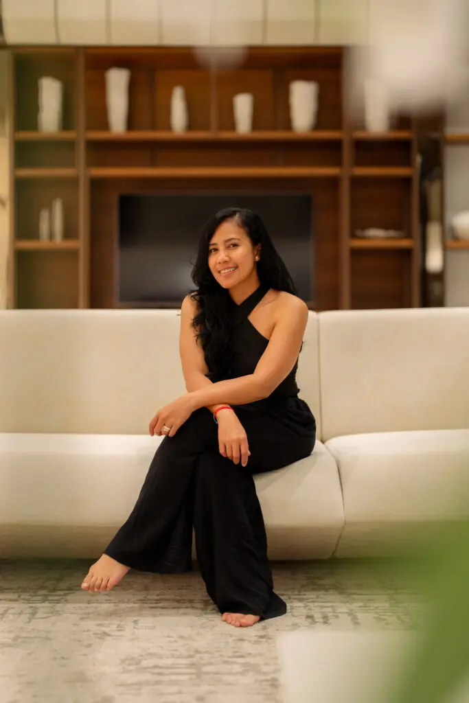 Smiling woman in black outfit seated on sofa